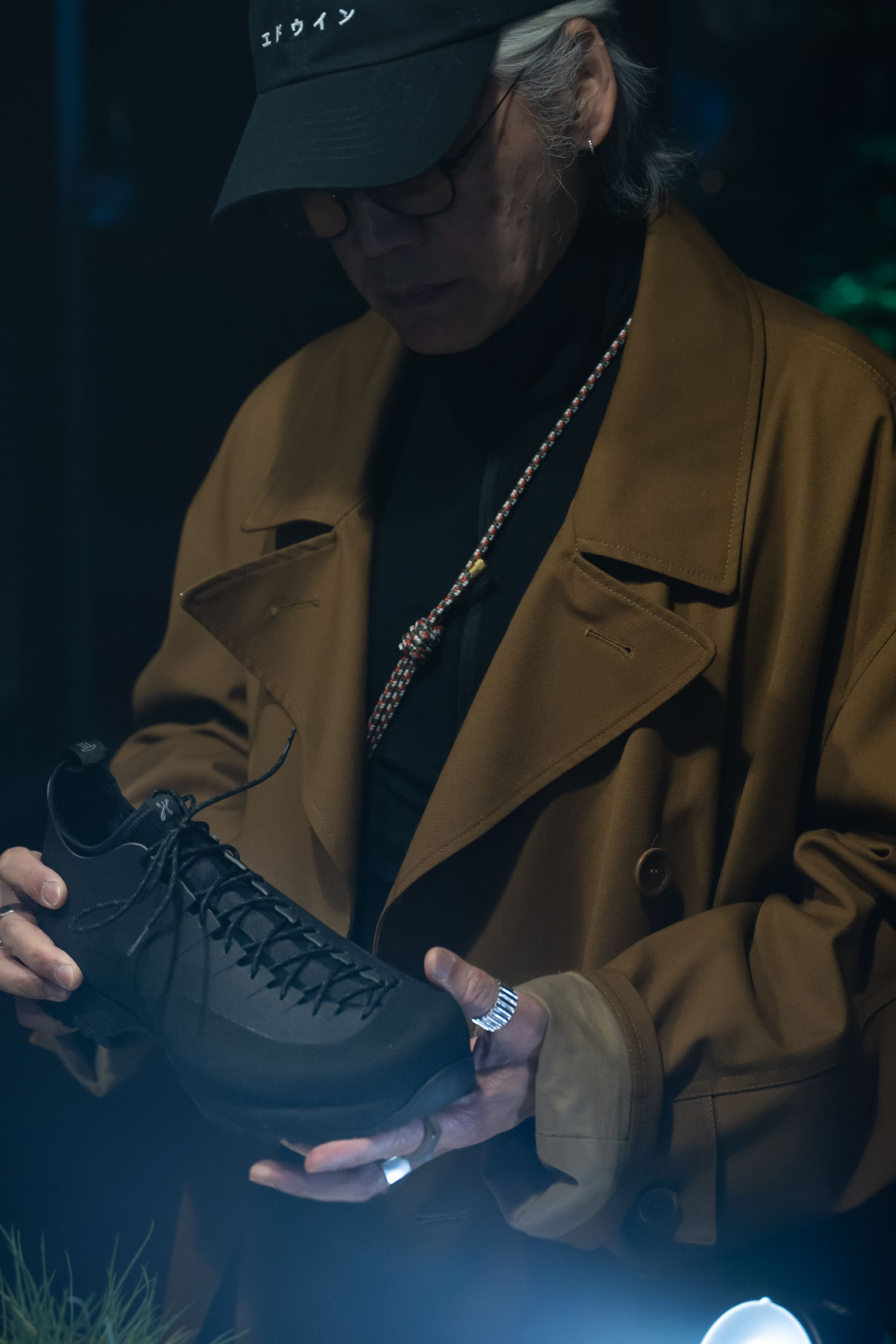 Guest holding a black shoe under a spotlight at the Houdini × Demon Silvestre launch at ARYS Store